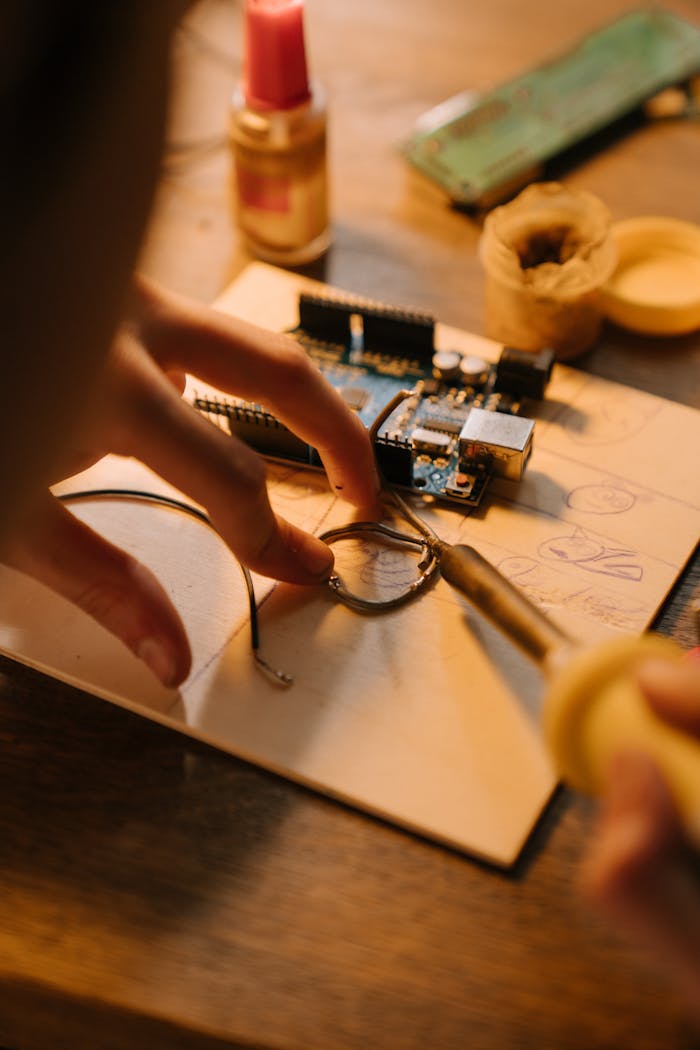 Hands intricately repairing a circuit board with a soldering iron under warm lighting.